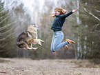 woman jumps with Eurasian Dog in the air