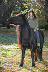 woman rides Frisian horse