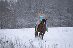 Woman riding through the snow in a dress