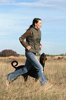 woman runs with Doberman Pinscher