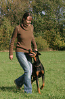 woman walks with Doberman Pinscher