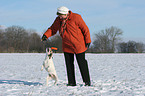 woman plays with Parson Russell Terrier in the snow