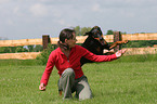 Doberman Pinscher jumps over the arm of a woman