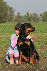 girl is snuggling a Rottweiler