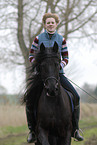 woman rides Frisian horse