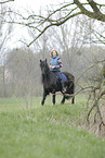 woman rides Frisian horse