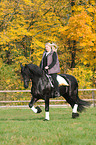 woman rides Frisian horse