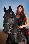 woman rides Frisian horse