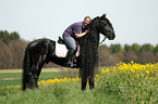 woman rides Frisian horse