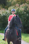 woman rides Friesian Horse