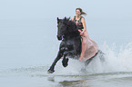 woman rides Friesian horse