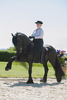 woman rides Friesian horse