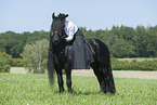 woman rides Friesian horse