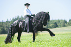 woman rides Friesian horse