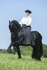 woman rides Friesian horse