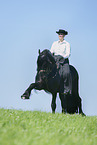 woman rides Friesian horse