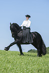 woman rides Friesian horse