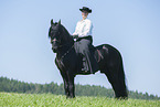 woman rides Friesian horse