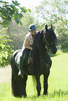 woman rides Friesian horse