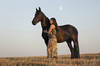 young woman with friesian mare