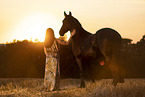 young woman with friesian mare