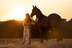 young woman with friesian mare