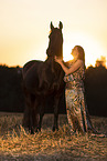 young woman with friesian mare