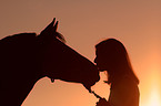 woman kisses horse in sundown