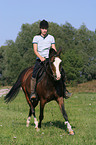 woman rides German Riding Pony in the meadow